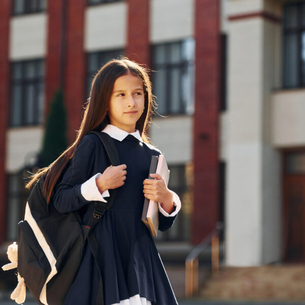 Schoolgirl is walking outside near school building