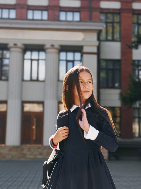 Schoolgirl is outside near school building